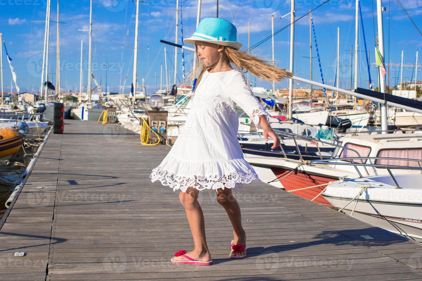 förtjusande liten flicka ha roligt i en hamn på sommar dag foto