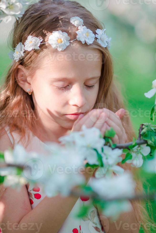 förtjusande liten flicka i blomning äpple träd trädgård på vår dag foto