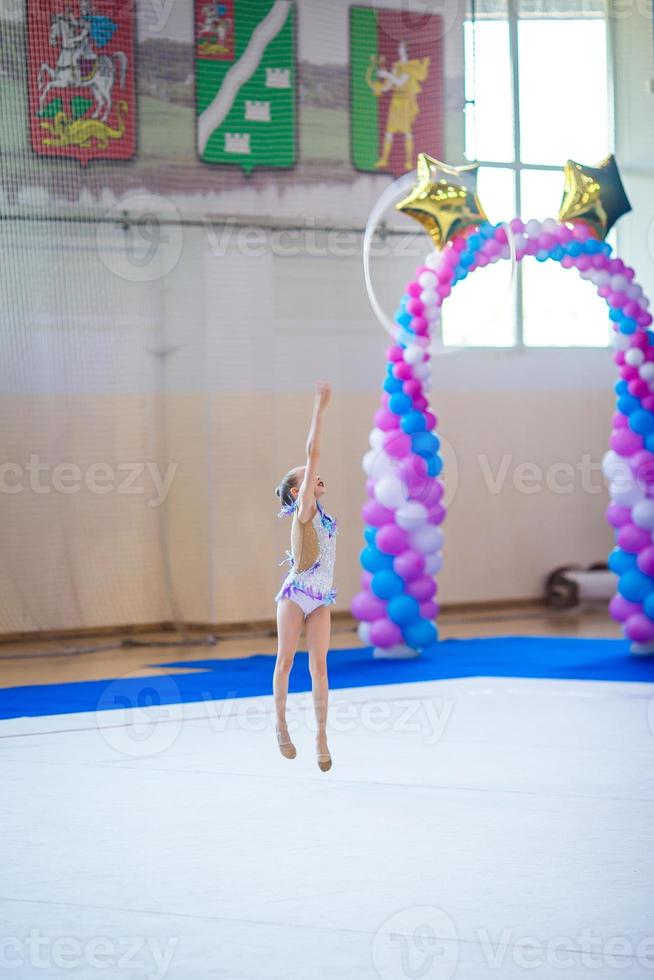 skön liten aktiva gymnast flicka med henne prestanda på de matta foto