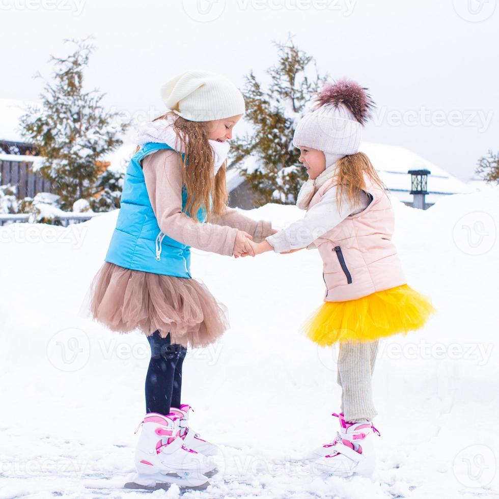 förtjusande liten flickor skridskoåkning på is rink i vinter- snö dag foto