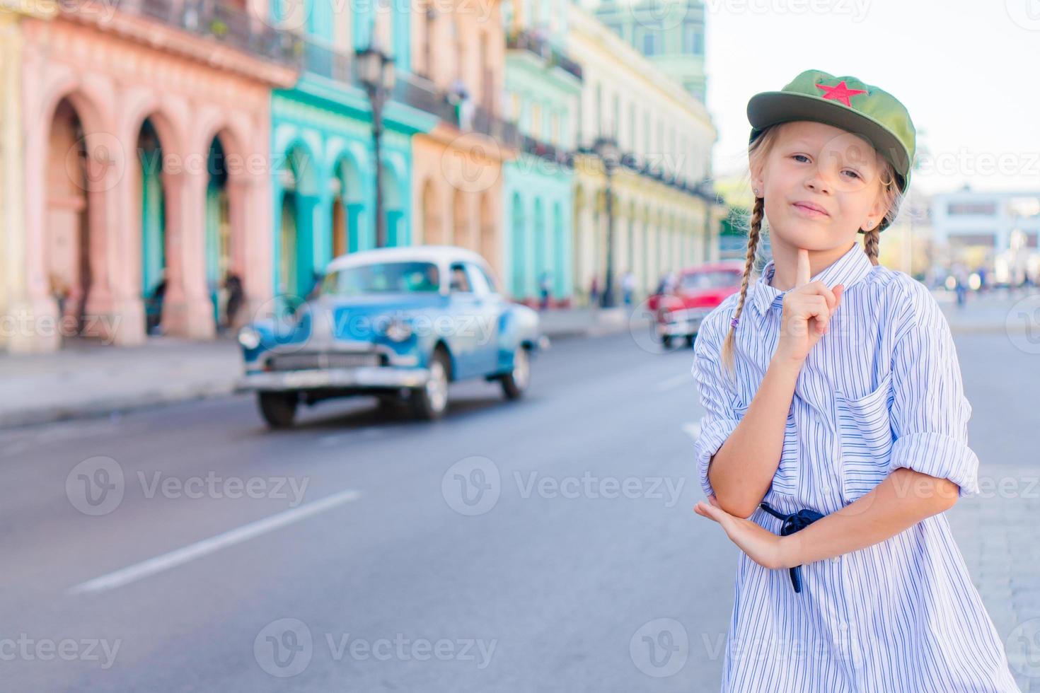 förtjusande liten flicka i populär område i gammal Havanna, kuba. porträtt av unge bakgrund årgång klassisk amerikan bil foto