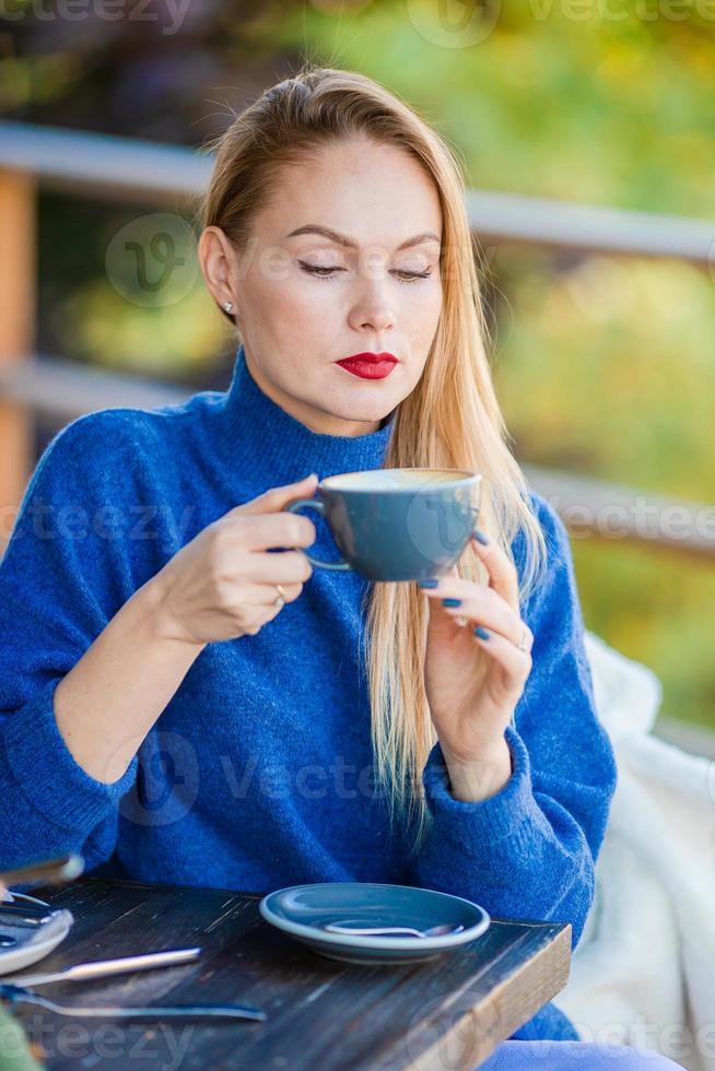 falla begrepp - skön kvinna dricka kaffe i höst parkera under falla lövverk foto