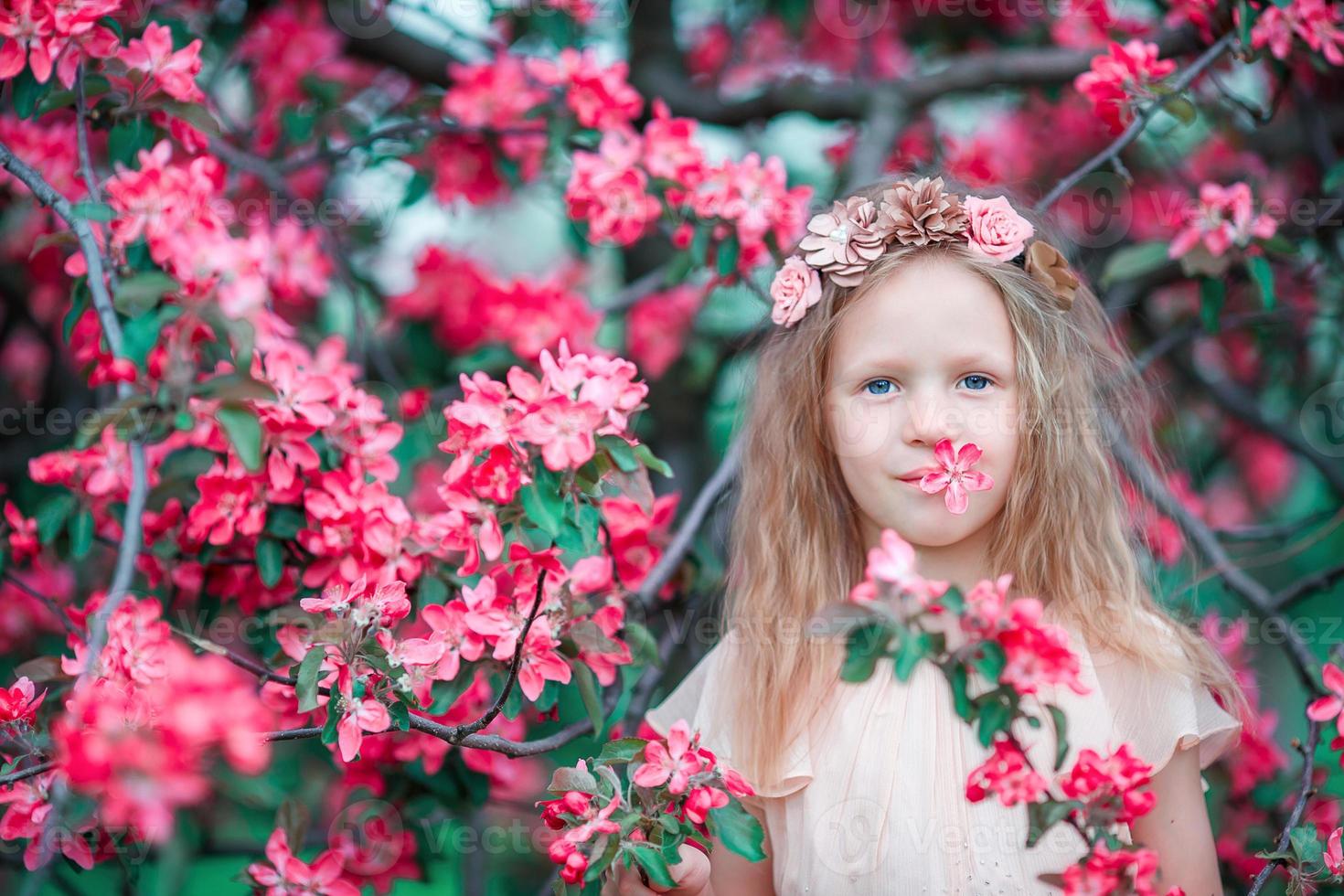 förtjusande liten flicka i en blommande vår äpple trädgård foto