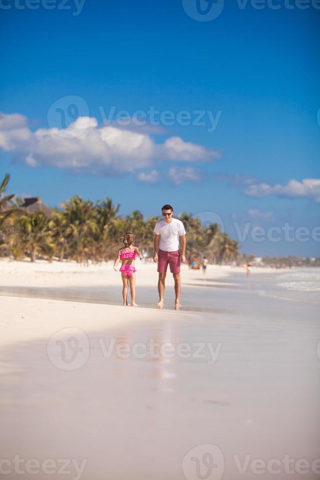 ung far och hans förtjusande liten dotter ha roligt på strand foto