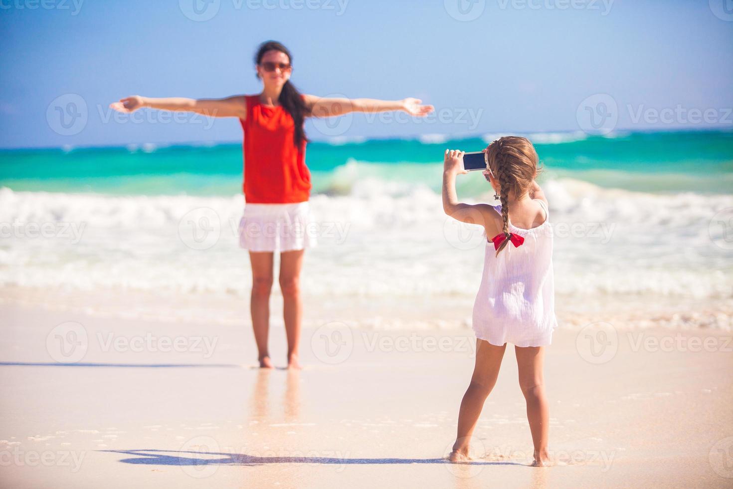 liten flicka fotografier henne mor på de strand foto