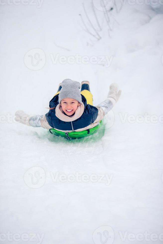 förtjusande liten Lycklig flicka sledding i vinter- snöig dag. foto