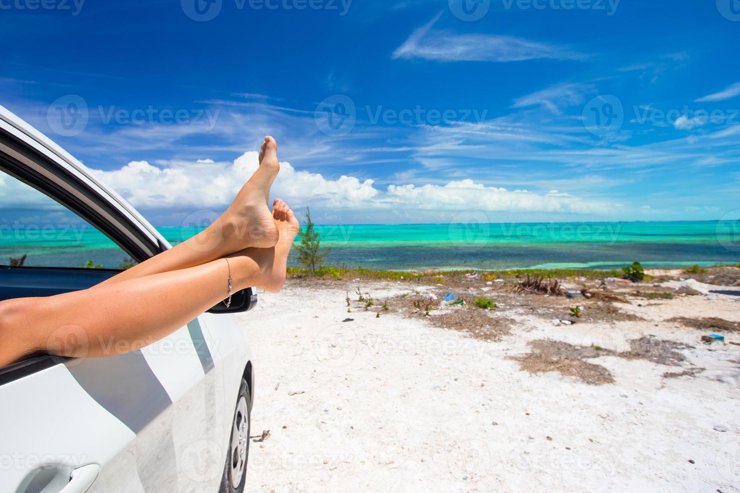kvinna barfota från de fönster av en bil på bakgrund tropisk strand foto