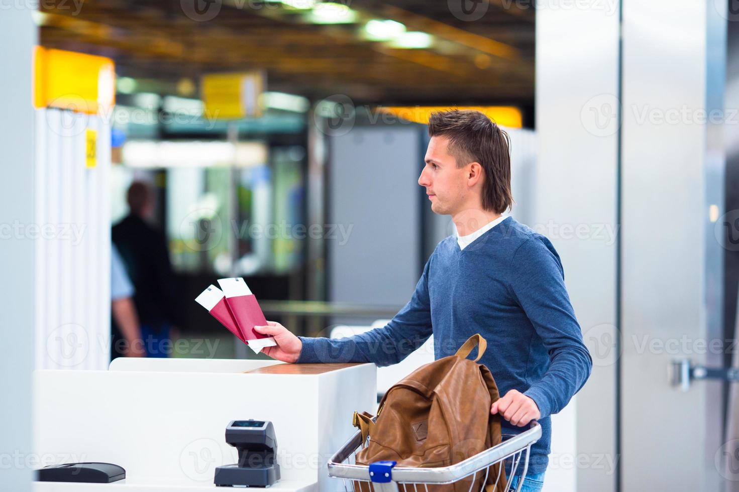 ung man med pass och ombordstigning passerar på de främre skrivbord på flygplats foto