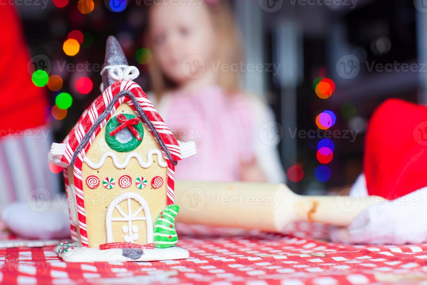 pepparkaka fe- hus för jul på bakgrund av barn och gran med krans foto