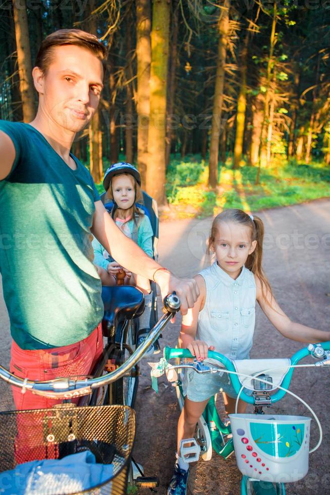 Lycklig familj cykling utomhus på de parkera foto