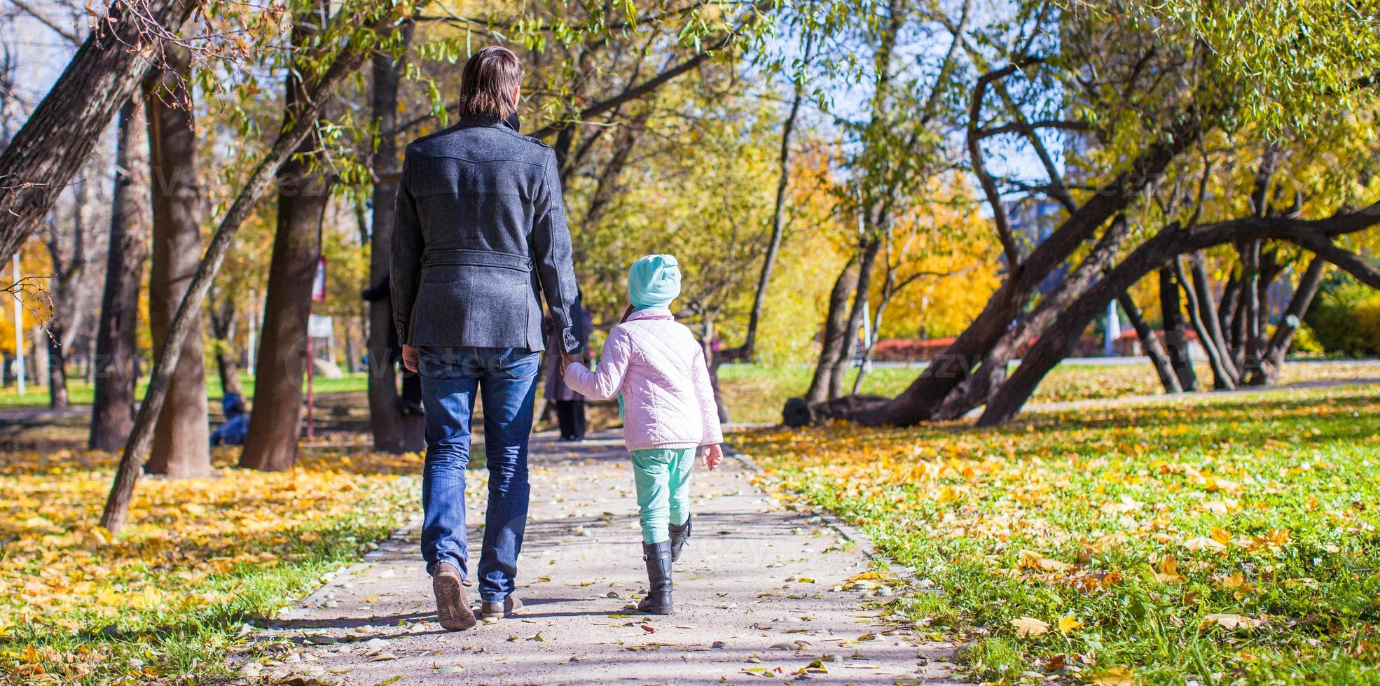 bak- se av ung far och liten flicka gående i höst parkera foto