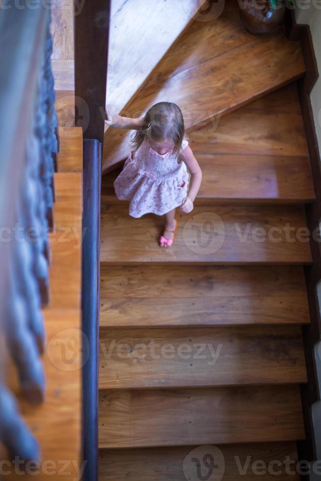 underbar liten flicka på de trappa i en stor hus foto