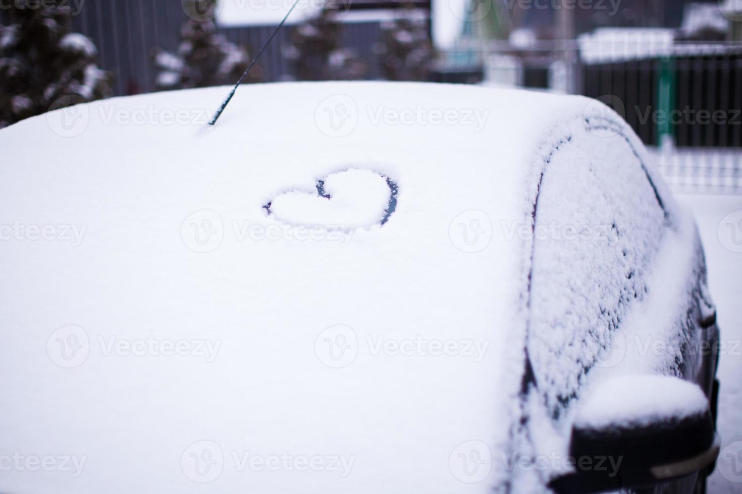 hjärta målad på snöig bil glas. foto
