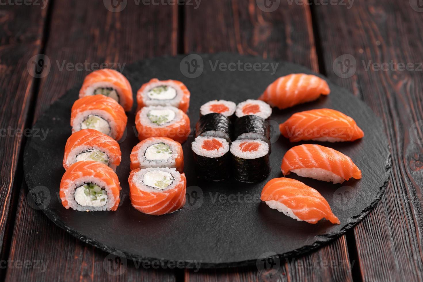 sushi uppsättning från topp på svart bakgrund närbild. ett sortiment av olika maki nigiri och rullar skaldjur soja sås foto
