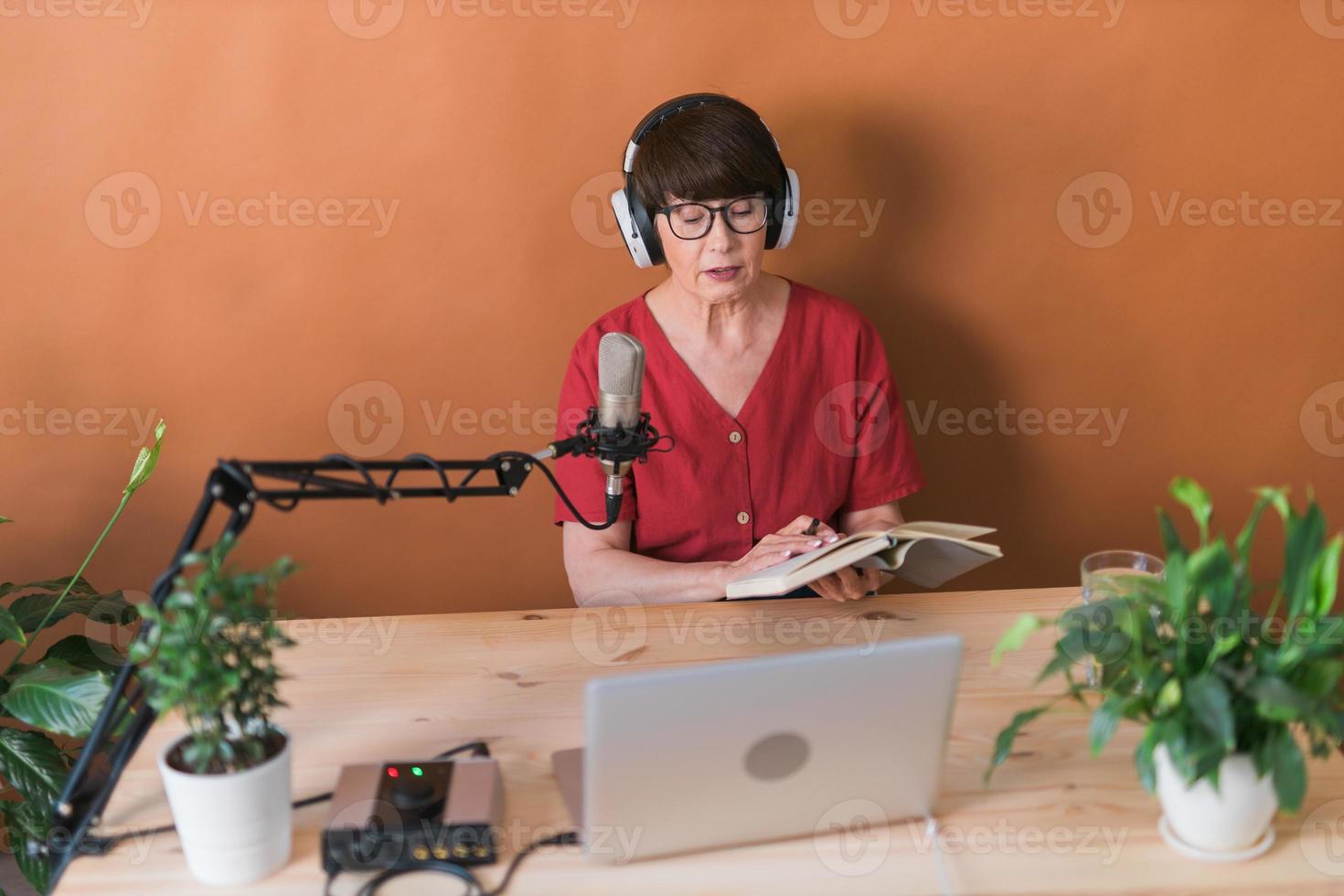 medelålders kvinna radio presentatör talande in i de mikrofon och läsning Nyheter - radio utsända uppkopplad begrepp foto