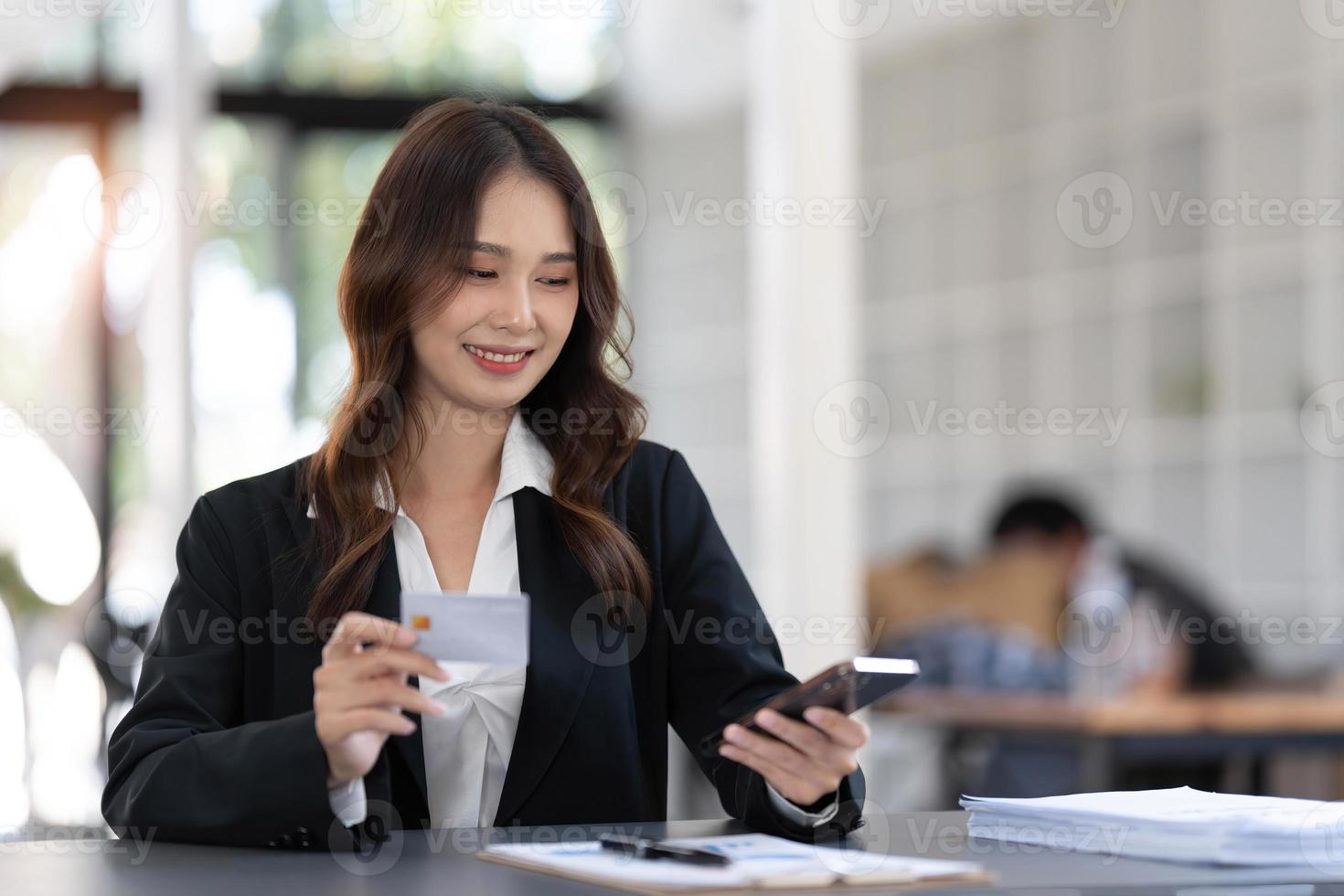 ung asiatisk kvinna betalande med kreditera kort på smart telefon på Hem kontor, uppkopplad betalning begrepp. foto