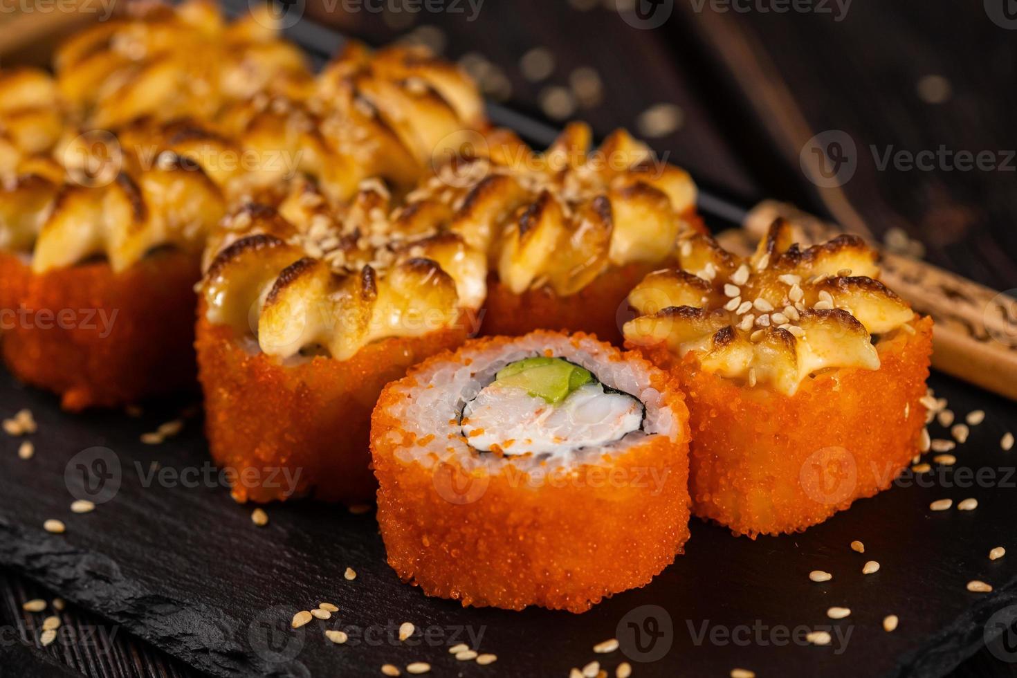 kalifornien sushi rulla med krabba, avokado och tobiko kaviar eras på svart styrelse närbild - japansk mat foto