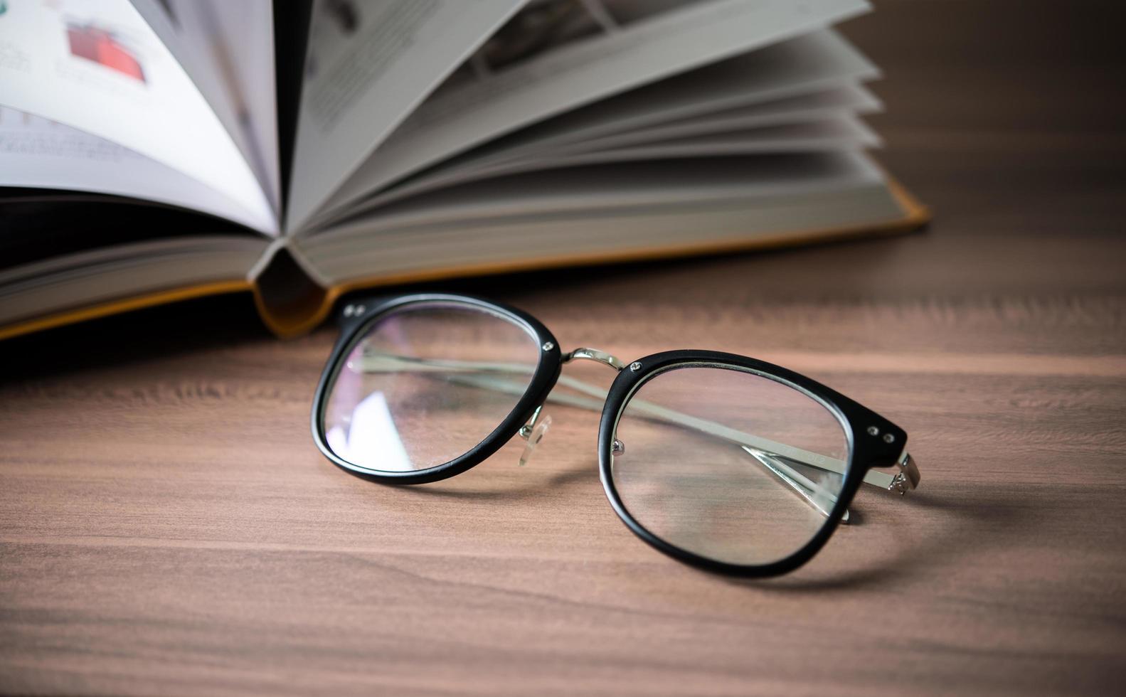 glasögon på ett träbord med böcker foto