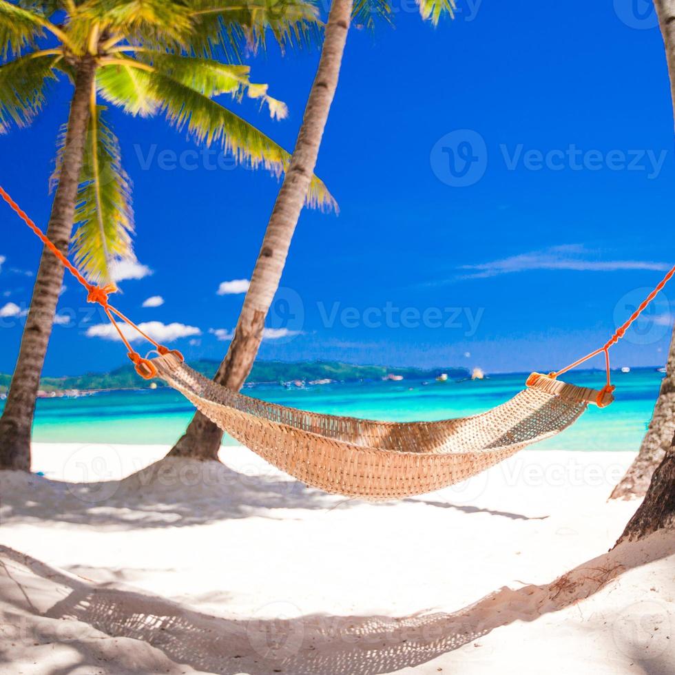halm hängmatta i skuggan av palm på tropisk strand vid havet foto