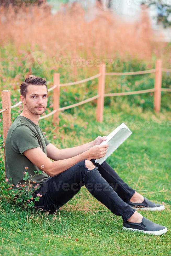 Lycklig ung urban man med bok utomhus foto