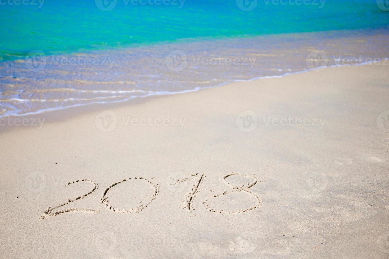 2018 handskriven på sandig strand med mjuk hav Vinka på bakgrund foto