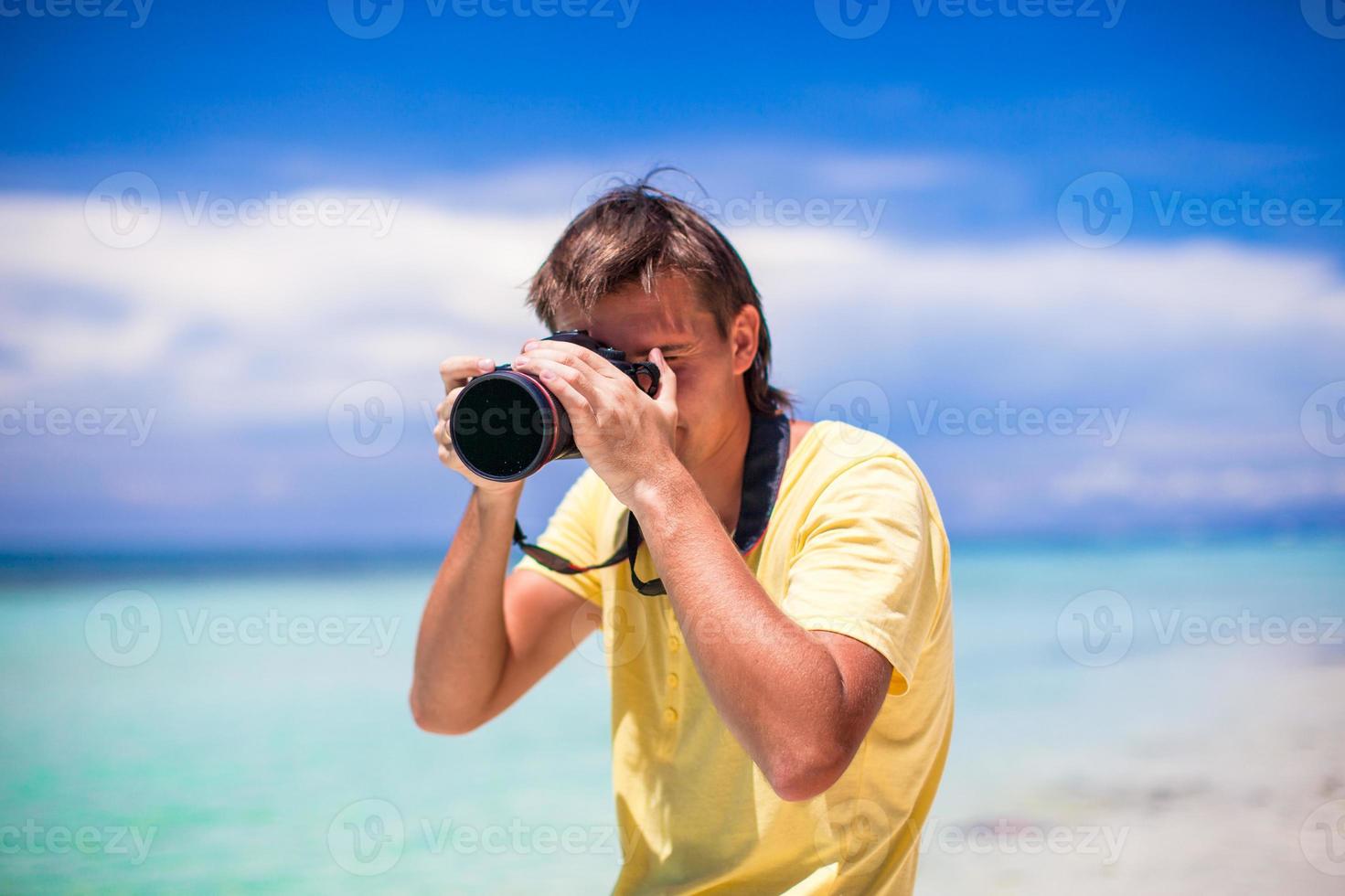 närbild av man med en kamera på vit sand strand foto