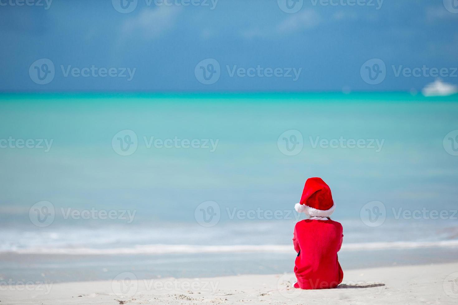 bedårande liten flicka i santa hatt på tropisk strand foto