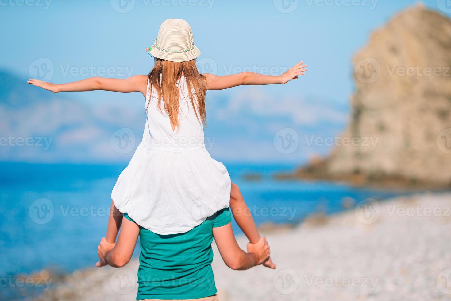 liten flicka och Lycklig pappa har roligt under strand semester foto