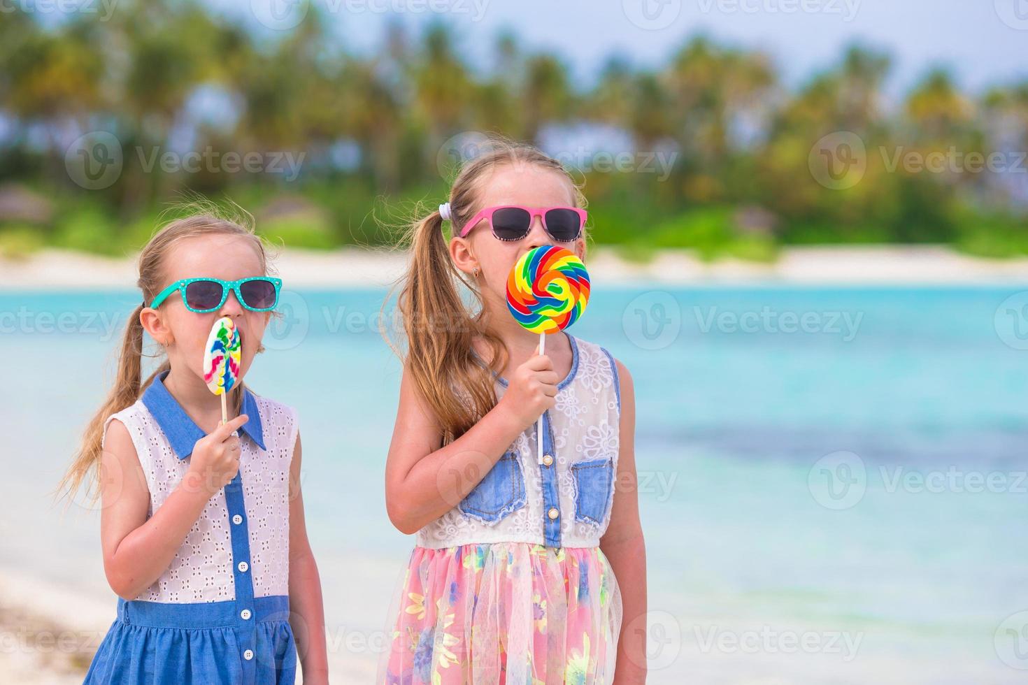 förtjusande liten flickor med ljus gott godis på vit strand foto