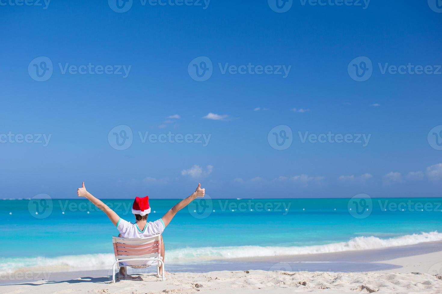 ung man i santa hatt under strand semester foto