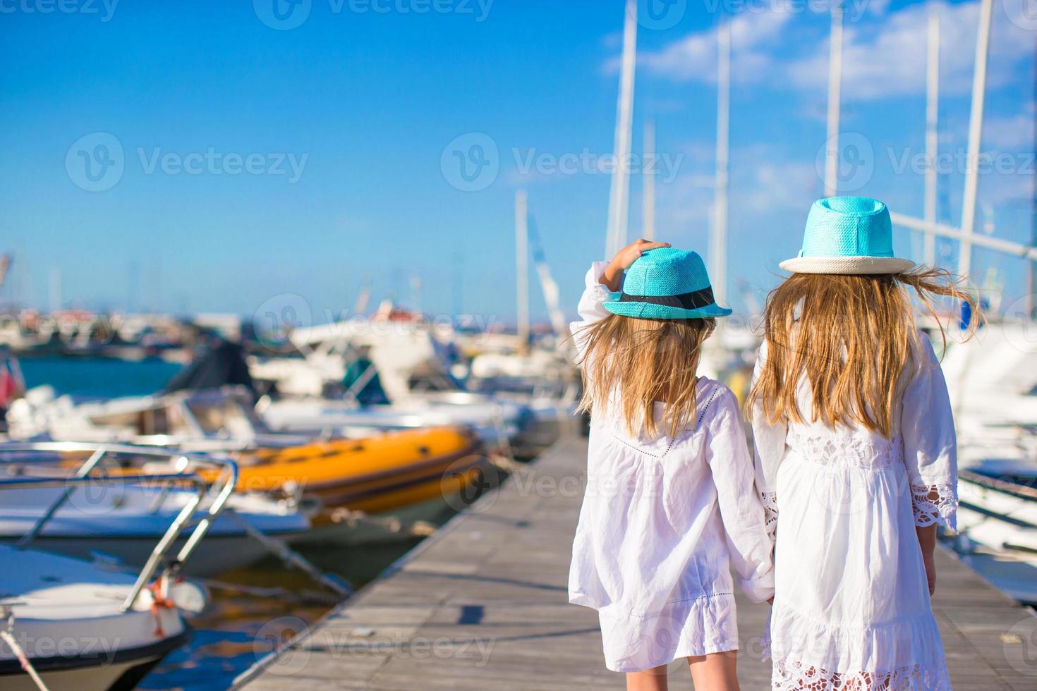 förtjusande liten flickor gående i en hamn under sommar semester foto