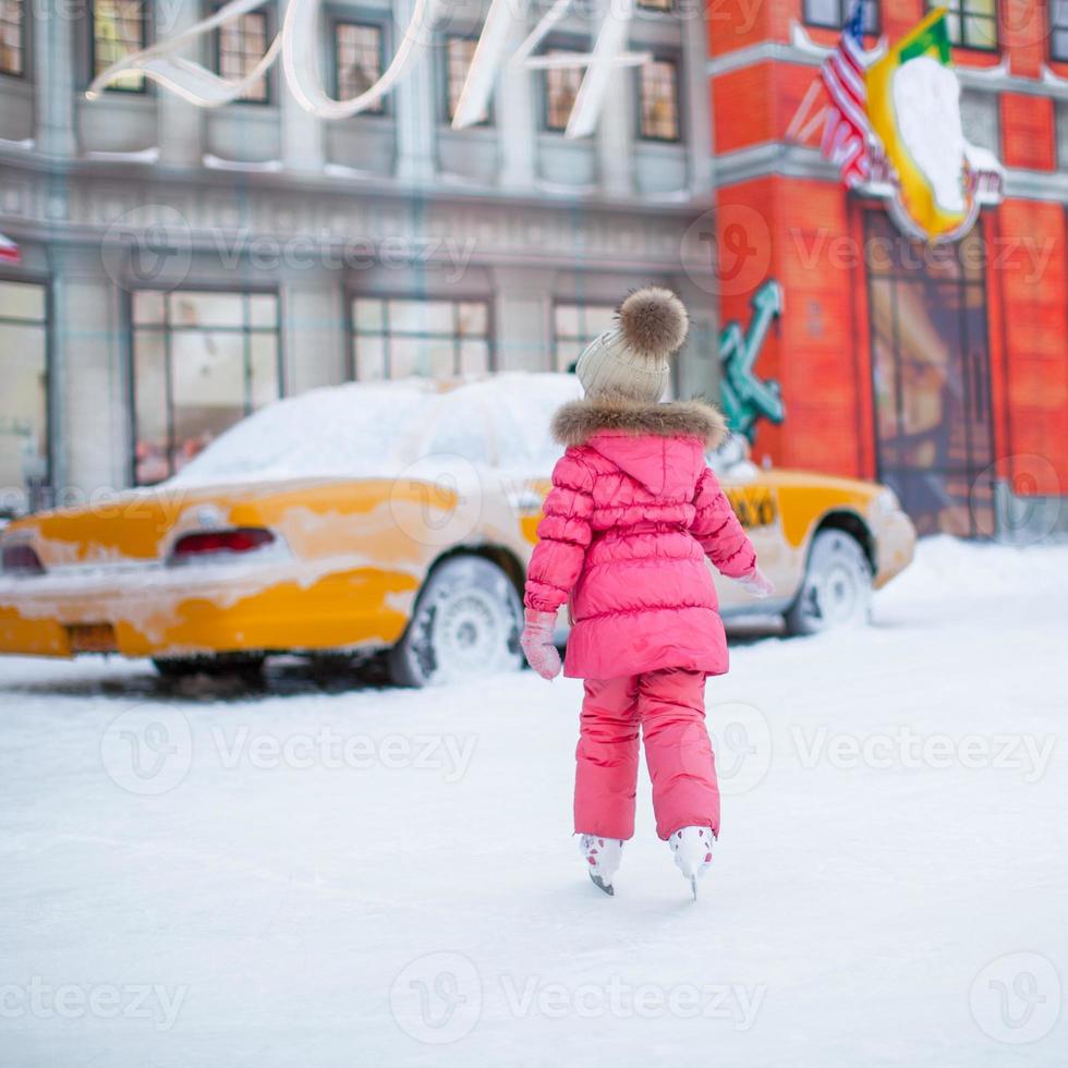 tillbaka se av förtjusande liten flicka njuter skridskoåkning på de isbana foto