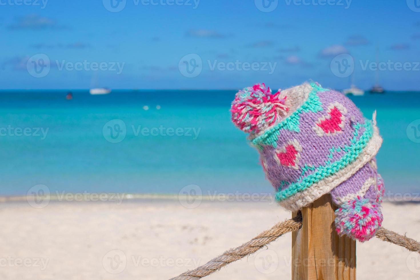 närbild värma stickat keps på staket på tropisk strand foto