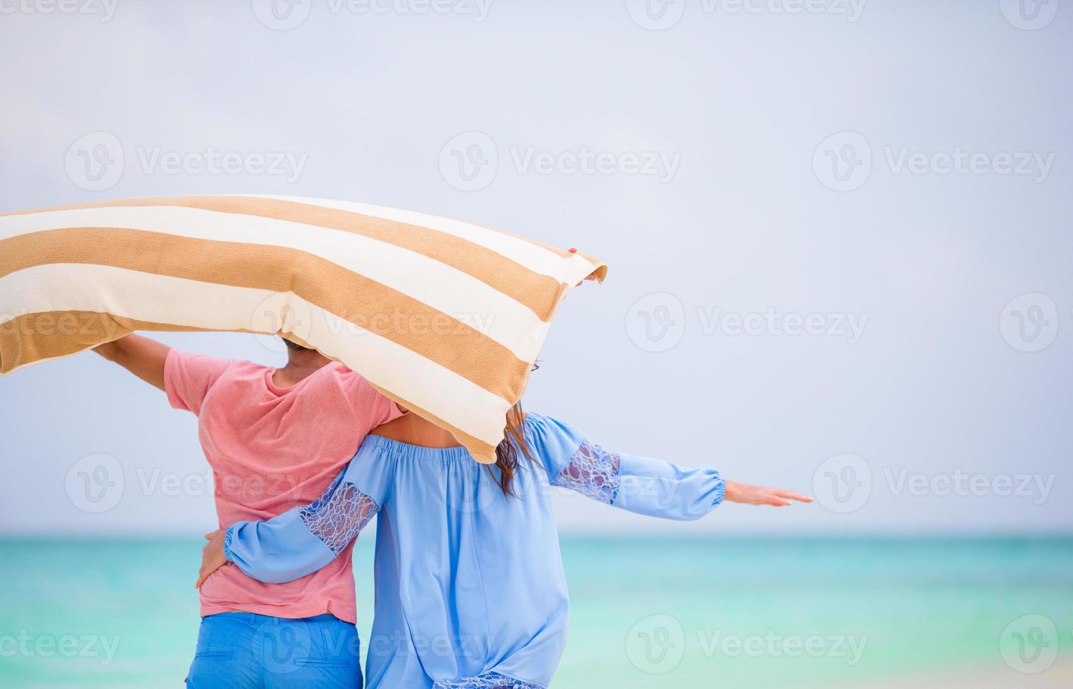 bak- se av ung par i smekmånad på vit strand foto