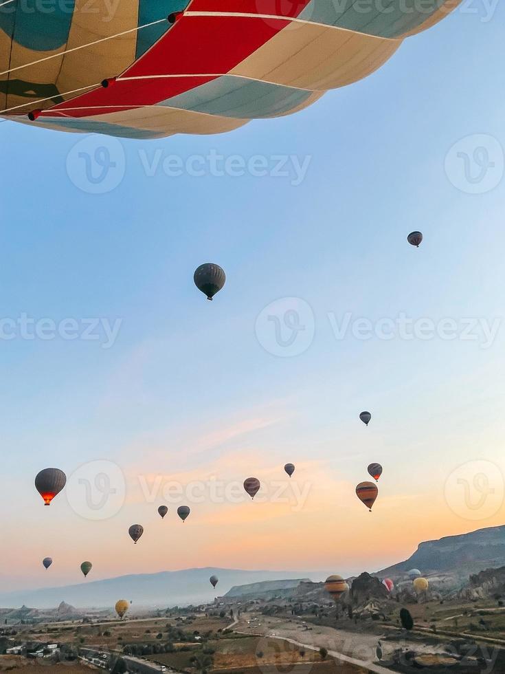 varm luft ballong flygande över klippig landskap i cappadocia med skön himmel på bakgrund foto
