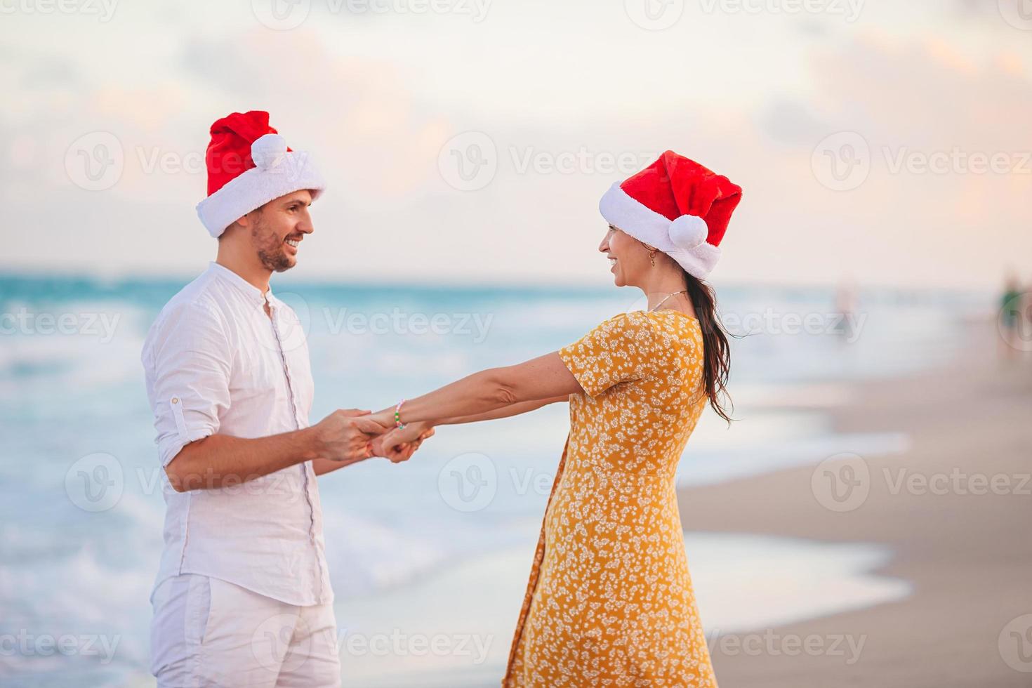 Lycklig par i santa hattar på jul strand semester foto