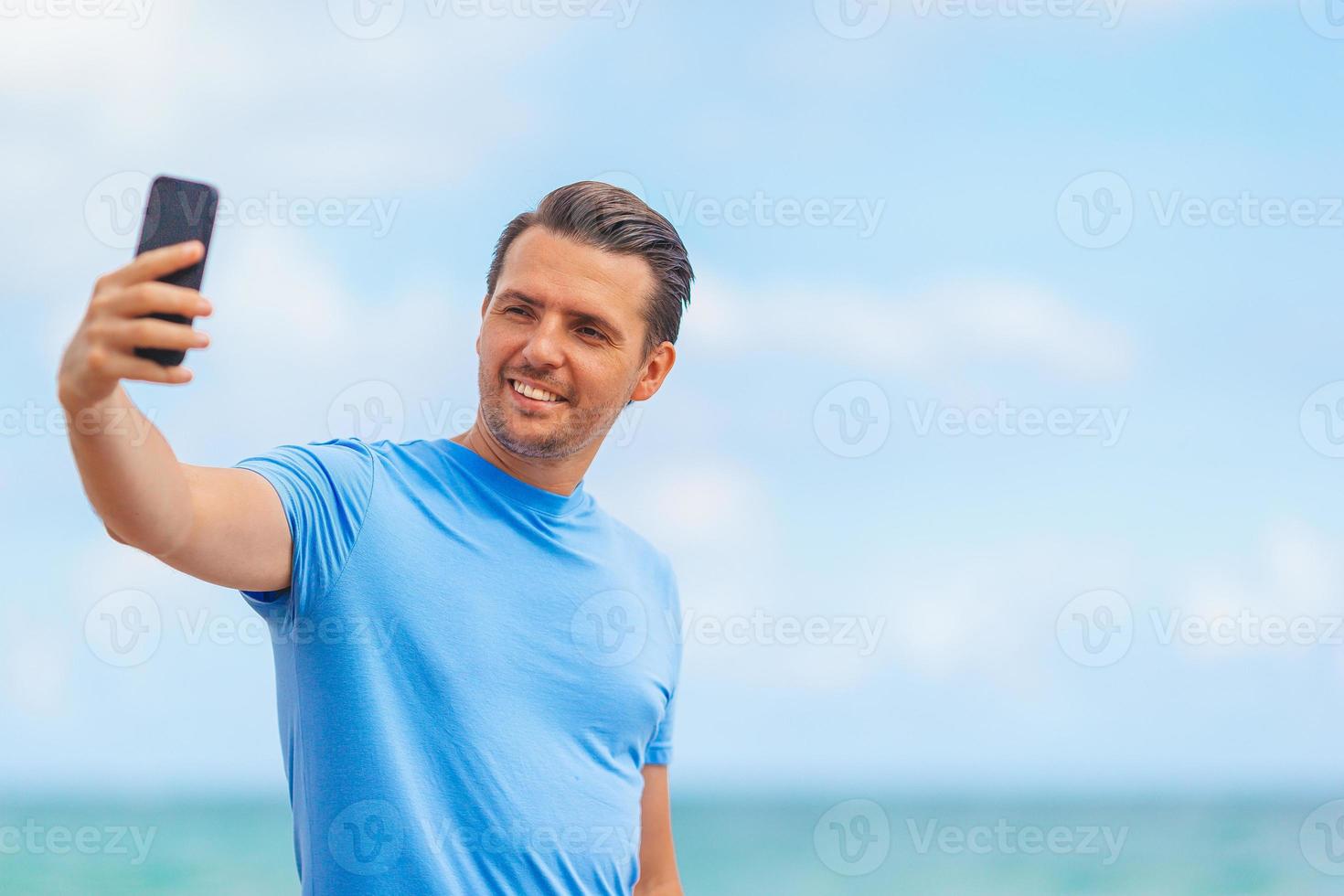 ung man tar selfie medan gående på de strand foto