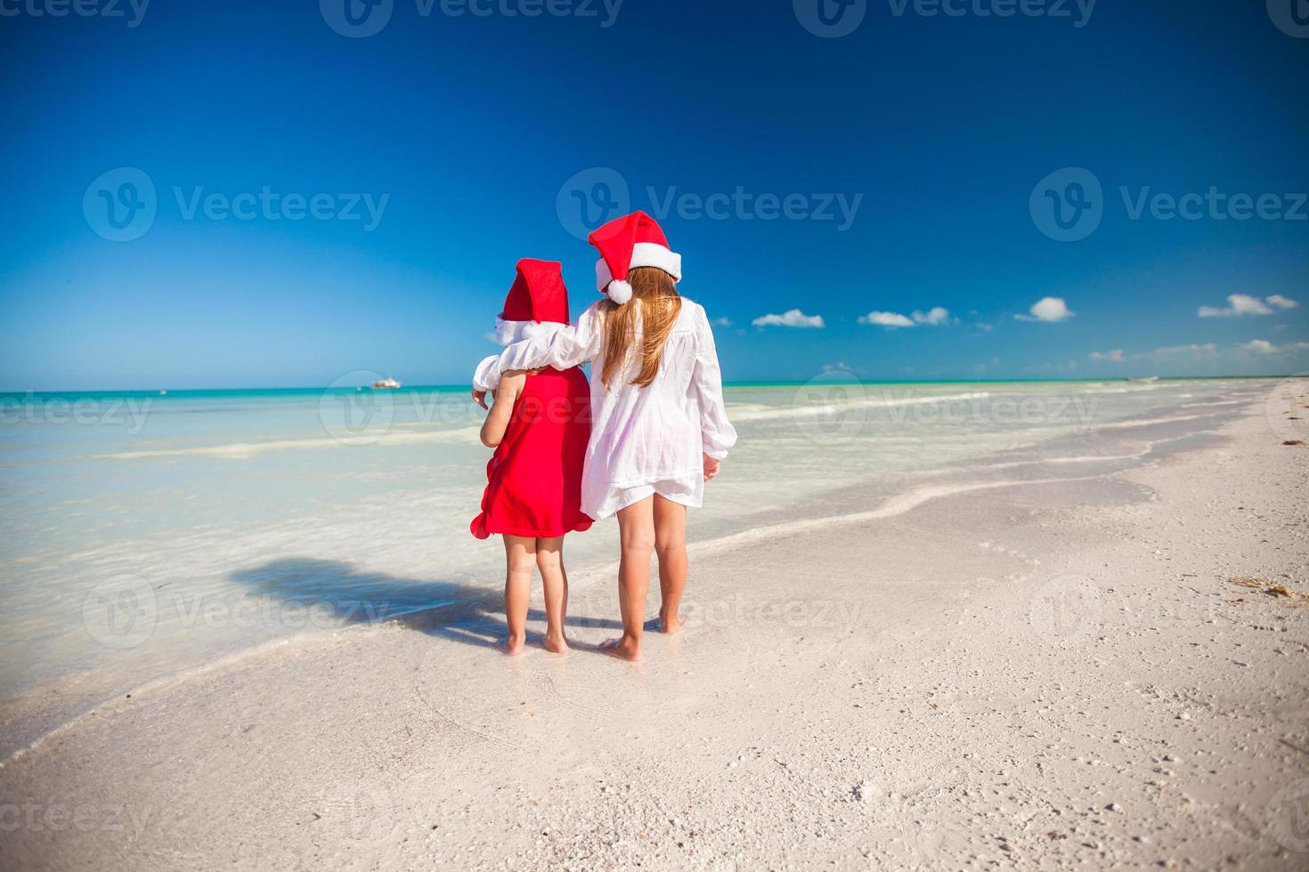 tillbaka se av liten söt flickor i jul hattar på de exotisk strand foto