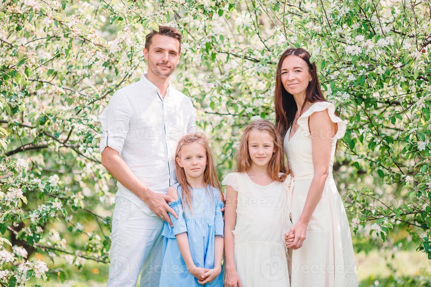 förtjusande familj i blomning körsbär trädgård på skön vår dag foto