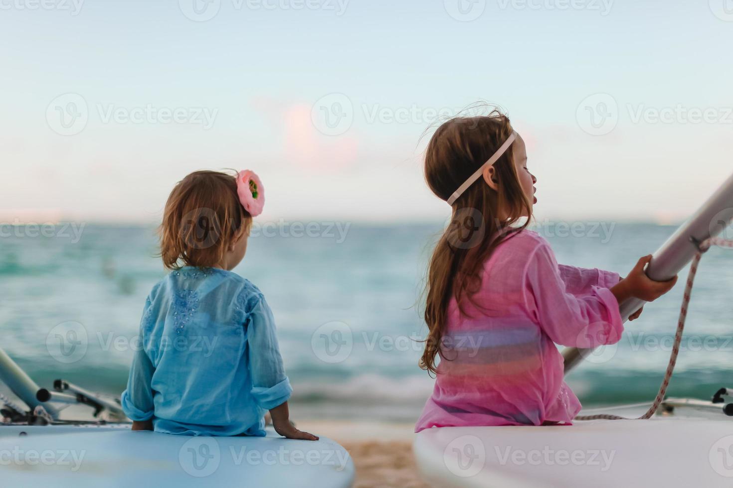 liten Lycklig rolig flickor ha en massa av roligt på tropisk strand spelar tillsammans. foto