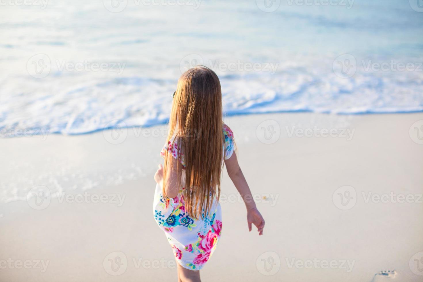 förtjusande liten flicka gående på vit tropisk strand foto