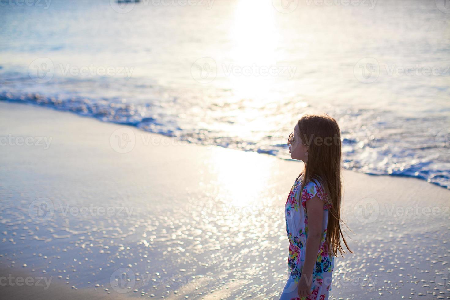 förtjusande liten flicka gående på vit tropisk strand foto