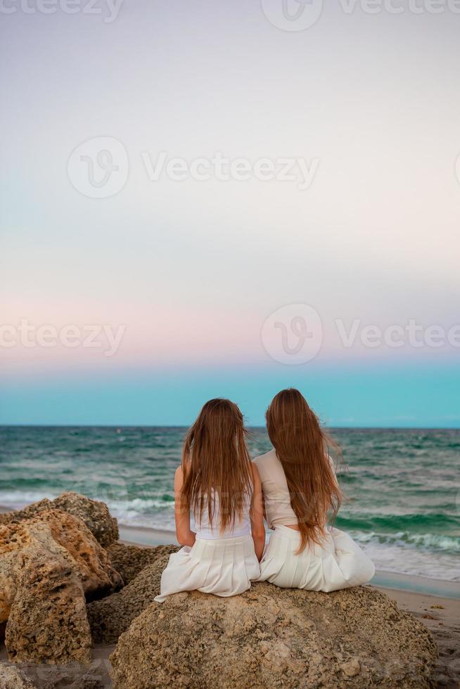 två systrar njut av solnedgång på de strand foto