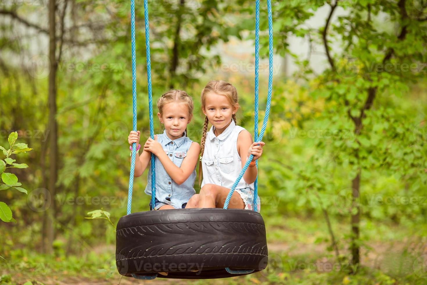 förtjusande liten flickor har roligt på en gunga utomhus foto