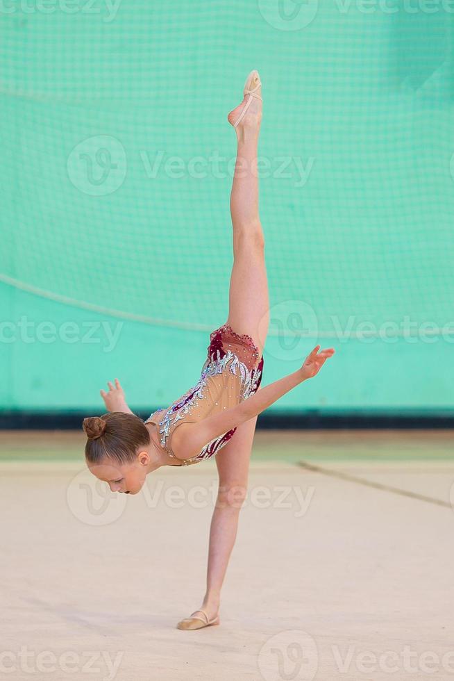 liten gymnast Träning på de matta och redo för tävlingar foto