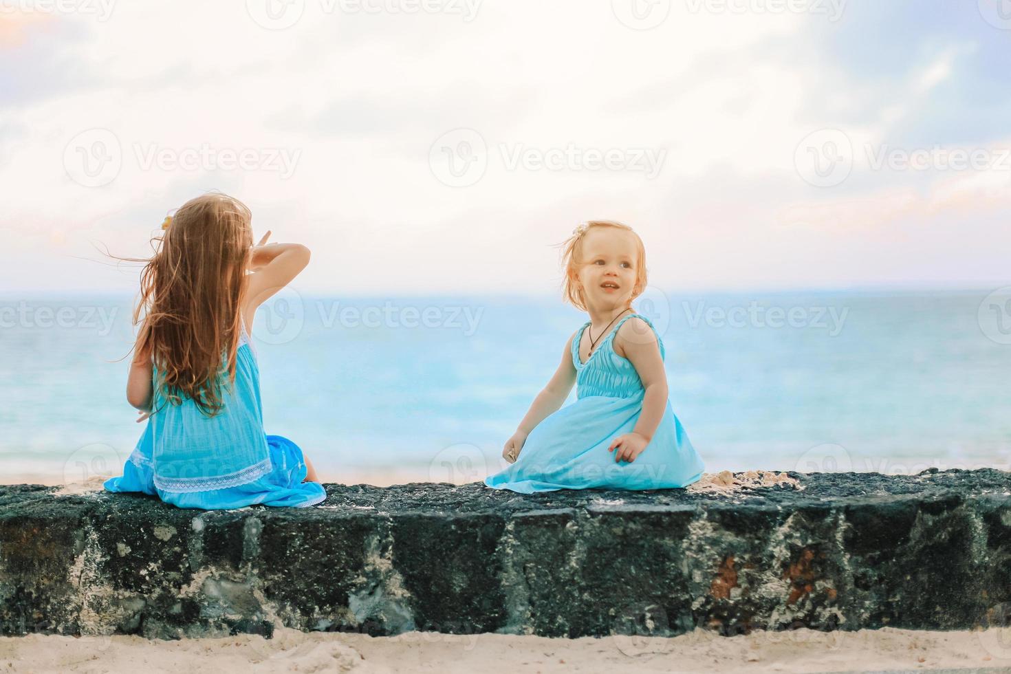 liten Lycklig rolig flickor ha en massa av roligt på tropisk strand spelar tillsammans. foto