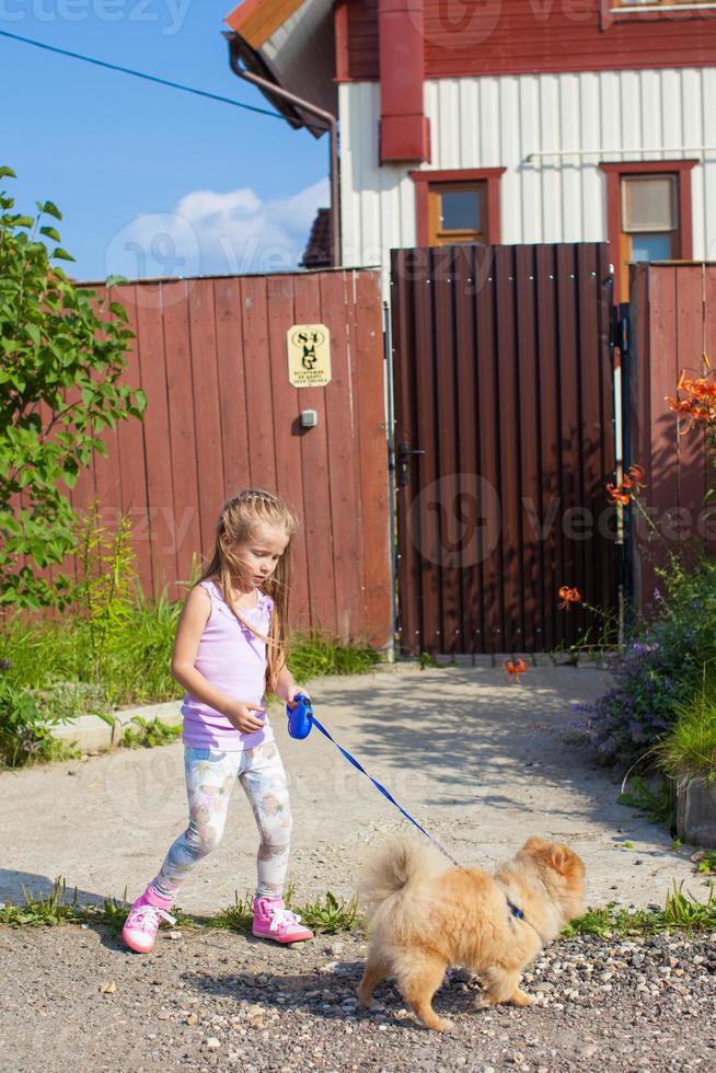 liten flicka gående med henne hund på en koppel foto