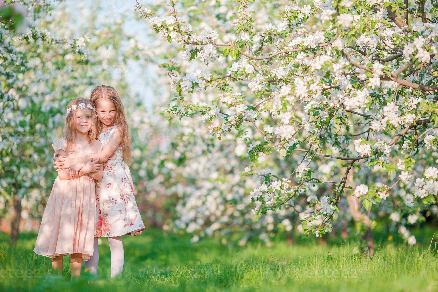 förtjusande liten flickor i blomning äpple träd trädgård på vår dag foto