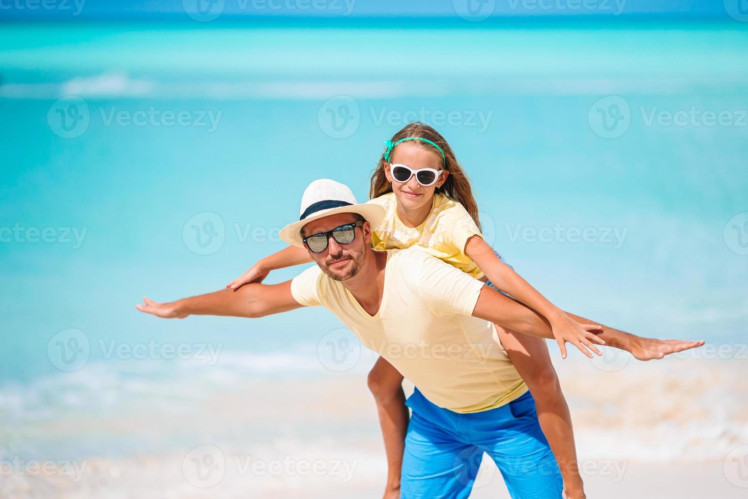 liten flicka och Lycklig pappa har roligt under strand semester foto