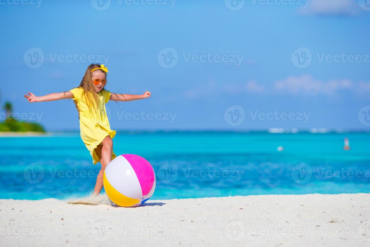 liten förtjusande flicka spelar på strand med boll utomhus- foto